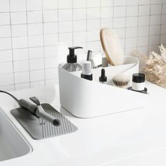 a white sink sitting next to a counter top with hair brushes and soaps on it