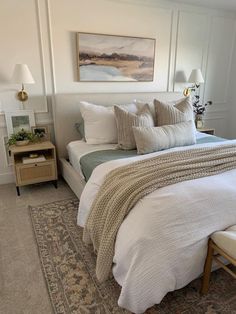 a bed with white sheets and pillows in a bedroom next to a painting on the wall