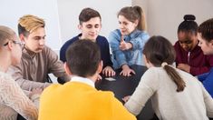 a group of young people sitting around a table