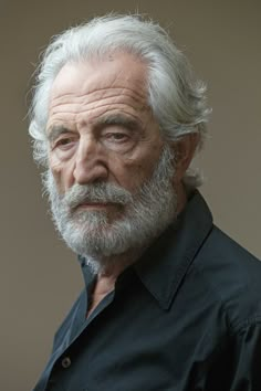 an older man with white hair and beard wearing a black shirt looking at the camera