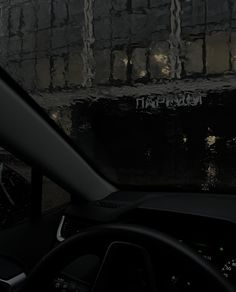 the interior of a car with graffiti on the wall behind it and steering wheel in view