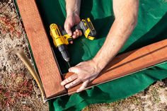 a man is holding a drill and screwdriver in his hand while laying on the ground