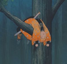 a person hanging upside down from a tree in the woods with an orange outfit on