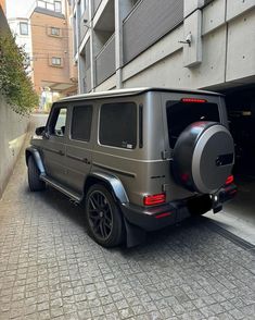 a grey jeep parked in front of a building next to a parking garage with its door open