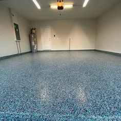 an empty garage with blue speckles on the floor and two doors in the background