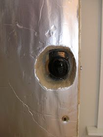 a metal door with a hole in the middle that has been painted silver and is being repaired