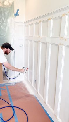 a man with a hose is painting the walls in a room that's being renovated