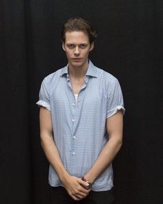 a man standing in front of a black background wearing a blue shirt and black pants