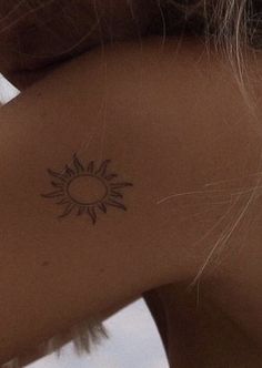 a woman with a small sun tattoo on her back shoulder