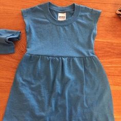 a blue dress sitting on top of a wooden floor next to a pair of shoes