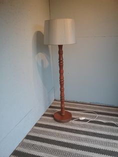 a lamp on the floor next to a wall