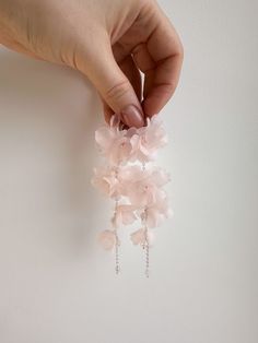 a person is holding some pink flowers in their hand and it looks like they are hanging from the ceiling