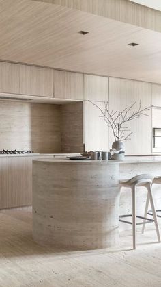 a kitchen with an island and stools in the middle of it, surrounded by wood paneling