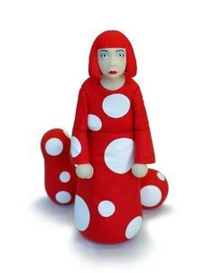 a red and white polka dot doll sitting on the ground with its legs spread out