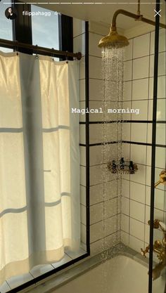 the shower head is running in front of the window and curtained tub with water coming from it