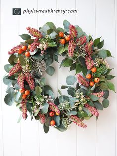 a wreath is hanging on the wall with berries and greenery