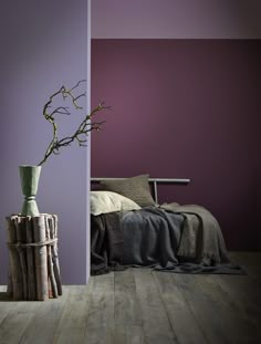 a bedroom with purple walls and wood flooring next to a plant in a vase