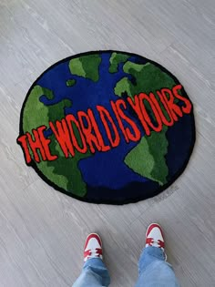 the world is yours door mat with red lettering on it and someone's feet standing next to it