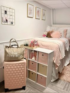 a pink suitcase sitting next to a white bed in a room with pictures on the wall