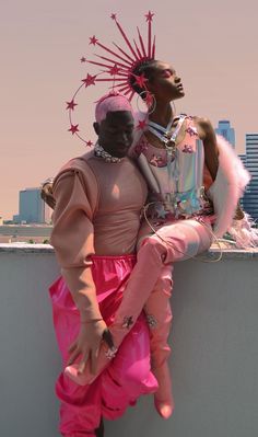 two people sitting on top of a wall next to each other wearing pink outfits and headgear