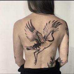 the back of a woman's body with tattoos on her upper and lower half