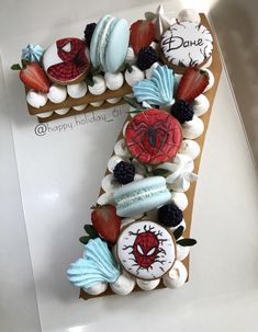 a cake shaped like the number one with decorations on it and strawberries in the shape of a spiderman