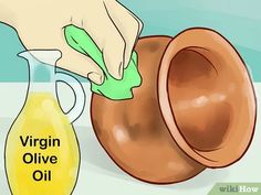 a person using an olive oil bottle to clean a vase