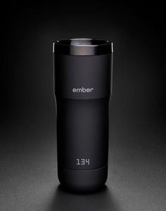 an empty black coffee cup sitting on top of a dark surface with the word ember printed on it