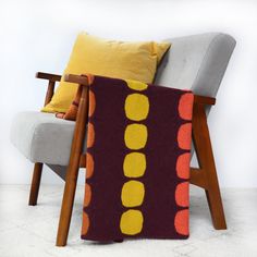 a chair with a knitted blanket on top of it next to a wooden frame