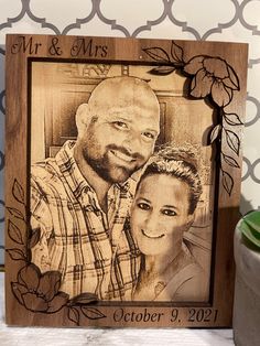 a wooden frame with an image of a man and woman on it next to a candle