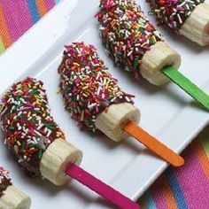 four popsicles with sprinkles on them are sitting on a white plate