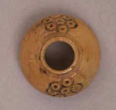 a wooden object with holes in the middle on a white surface and black circles around it