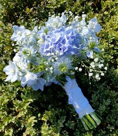 a bouquet of blue flowers sitting on top of green bushes