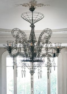 a large chandelier hanging from the ceiling in a room with windows and curtains