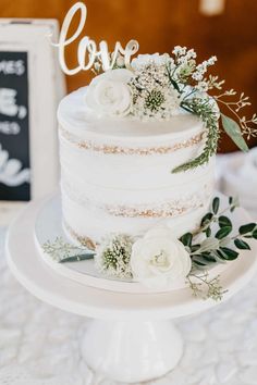 a wedding cake with white flowers and greenery on top