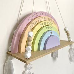 a rainbow shaped wooden sign hanging from the side of a wall