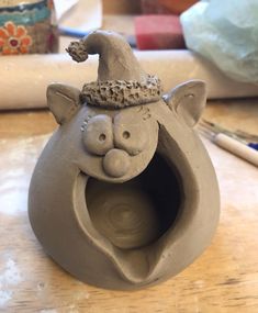 a clay sculpture of a cat with a hat on it's head and mouth