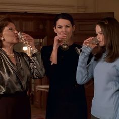 three women drinking from wine glasses in a living room