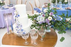 there is a wedding cake and wine glasses on the table with flowers in vases