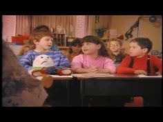 three children sitting at a table in front of an adult and one child with a stuffed animal