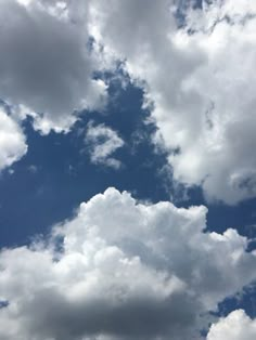 an airplane is flying through the cloudy blue sky with white clouds in the background,