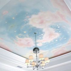 a chandelier hanging from the ceiling in front of a painted sky and clouds mural