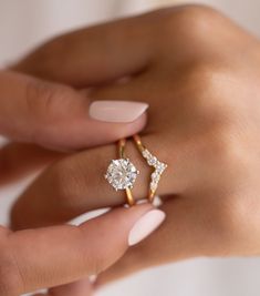 a woman's hand with two rings on her fingers and one ring in the middle