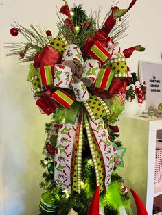 a christmas tree decorated with green and red ribbons, bows and decorations on top of it