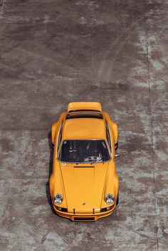 an overhead view of a yellow sports car parked in a parking lot with no one around