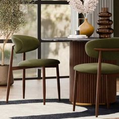 two green chairs sitting at a table in front of a vase with flowers on it