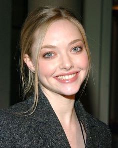 a woman with blonde hair and blue eyes smiling at the camera while wearing a blazer