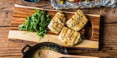 fish and vegetables on a cutting board next to a skillet with broccoli