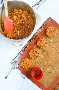 a bowl of oatmeal cookies next to a measuring cup with a spoon