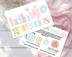 two business cards sitting next to each other on top of a white table with pink flowers